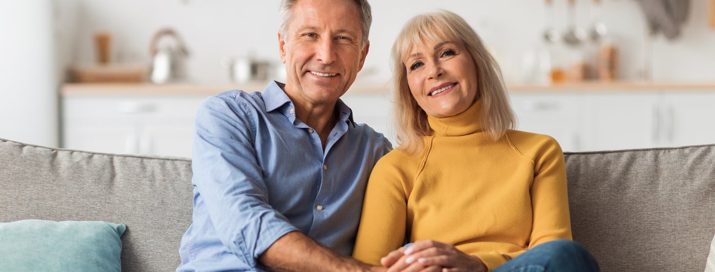 Smiling senior couple sitting together on a couch at home