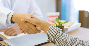 Dentist shaking hands with a patient across a desk