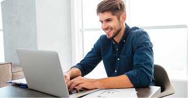 Smiling man working on a laptop at a desk
