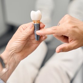 Patient pointing to a model of a dental implant with crown